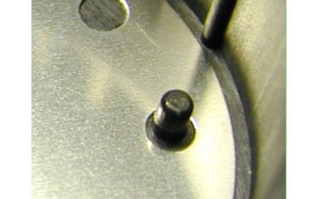 Blech-Stanzteil, das durch einen heißverstemmten Pin fixiert wird.