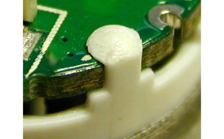Kunststoffpins werden einseitig auf eine Leiterplatte umgeformt um diese auf dem Kunststoffkörper dauerhaft zu fixieren.